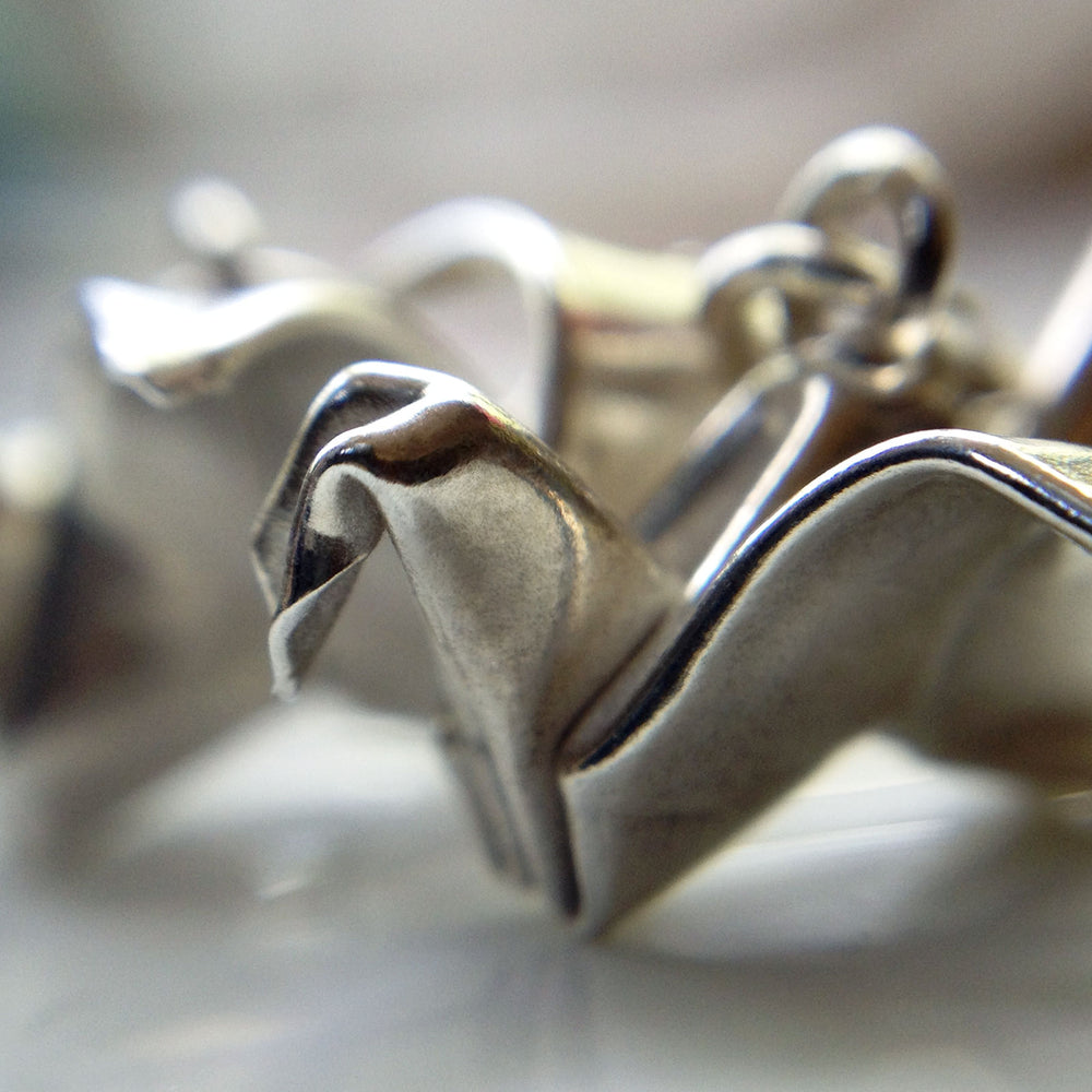 Silver origami peace crane earrings by Azulie, closeup view of cranes