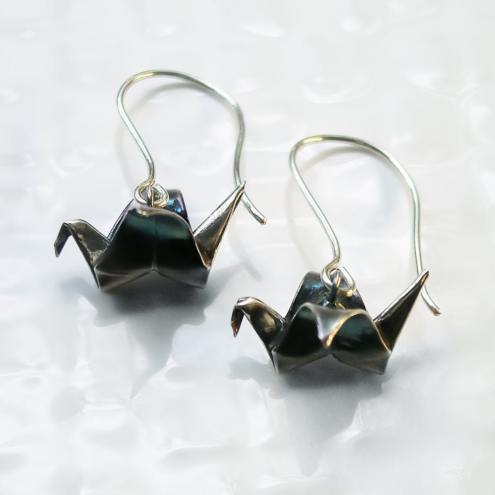 Patina silver origami peace crane earrings by Azulie, suspended from silver ear-wires