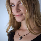 Fine silver origami pendant by Azulie, intricate hexagon design with a soft gunmetal patina, set with a Japanese creamy white pearl, on a black stainless steel multi-strand necklace, shown on model