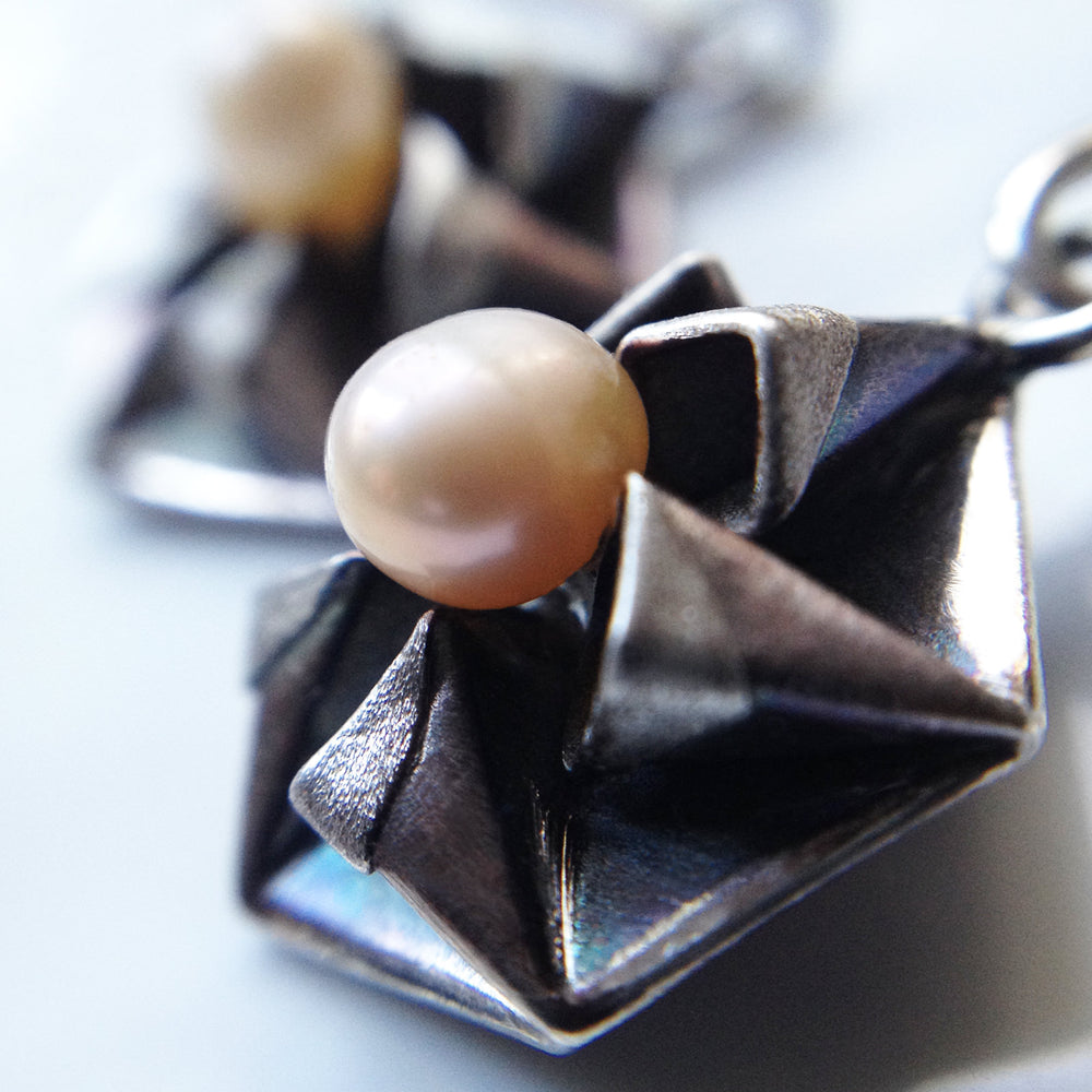 Fine silver origami earrings by Azulie, intricate hexagon design with a soft gunmetal patina and 4mm Japanese pale pink pearls, closeup view